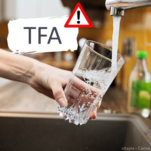 Hand hält ein Glas unter laufendem Wasserhahn, mit TFA-Warnsymbol als Hinweis auf mögliche Trifluoressigsäure im Trinkwasser.