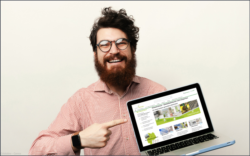 Eion sympathischer, glücklicher Mann deutet auf duie Startseite von Checknatura auf seinem Laptop.