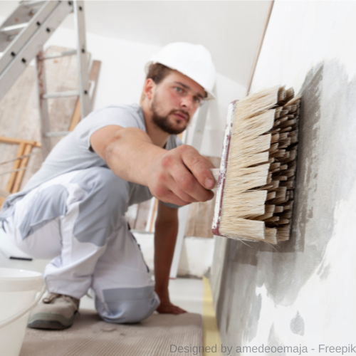 Ein Maler überstreicht mit einem Pinsel Schimmel auf einer weißen Wand.