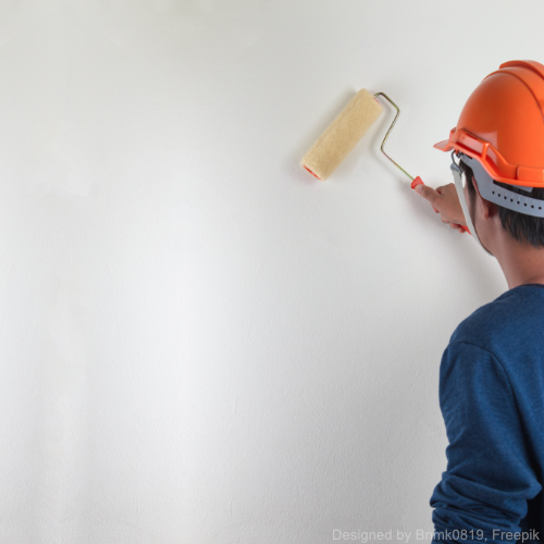Ein Mann mit Helm bemalt eine weiße Wand mit Antischimmelfarbe.