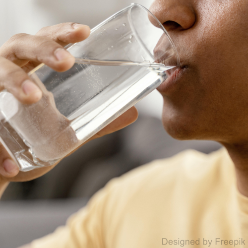 Ein Mann trinkt Trinkwasser aus einem Glas.