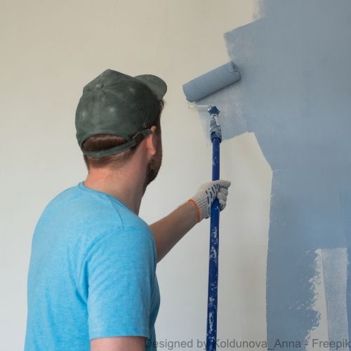 Ein Mann in blauem T-Shirt streicht eine Wand mit blauer Farbe