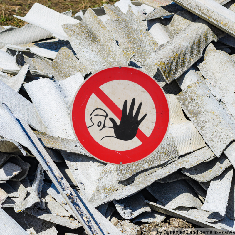 Zerbrochene Dachziegel mit Asbest und einem Warnschild darüber.