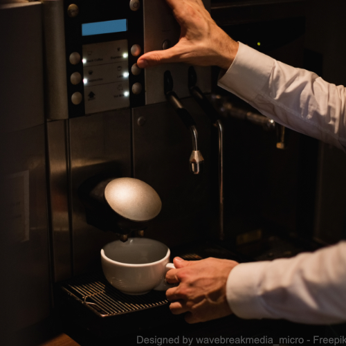 Mann drückt die Taste eines Kaffeevollautomaten, in dem sich Schimmel befindet