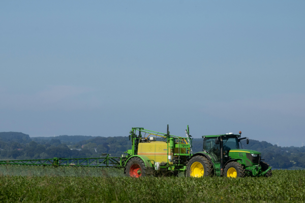 Traktor der eine Pferdeweide düngt.
