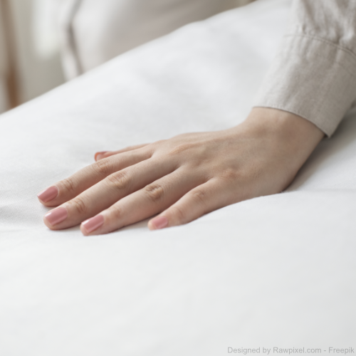Eine Frauenhand streicht über eine saubere Matratze