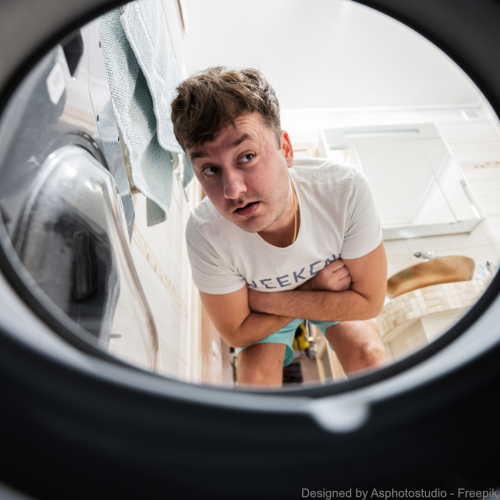 Ein Mann schaut skeptisch in eine Waschmaschine