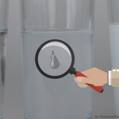 Trübes Wasser in einem Glas mit einer Lupe.