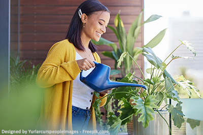 Eine Frau gießt die Blumen auf ihrem Balkon.